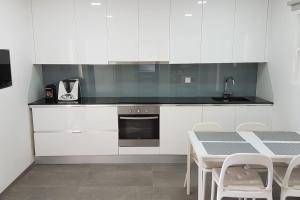 a kitchen with white cabinets and a table with chairs at Casa da Prelada in Amarante