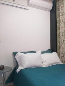 a bed with a white pillow and a table at Suite Grande Rio in Duque de Caxias
