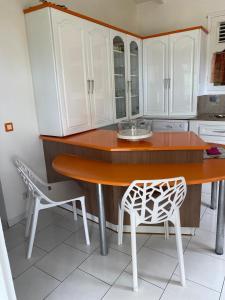 eine Küche mit weißen Schränken, einem Holztisch und einem Stuhl in der Unterkunft CHEZ Lise et RORO in Pointe-Noire