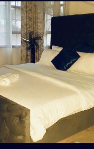 una camera da letto con un letto con lenzuola bianche e un ventilatore di Kisumu 3 bedroom Apartment Elegant a Kisumu