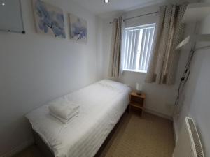 um quarto com uma cama com lençóis brancos e uma janela em J's House em Nottingham