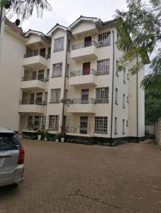 un grande edificio bianco con un'auto parcheggiata di fronte di Kisumu 3 bedroom Apartment Elegant a Kisumu