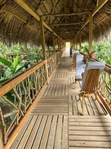 a wooden walkway with chairs and a straw roof at Tropical Magnolia 