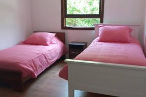 a bedroom with two beds with pink sheets and a window at Casa en cerro, playa, piscina y vista insuperable in El Convento
