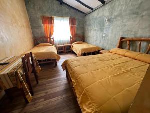 een kamer met 3 bedden en een raam bij Hotel Achik Wasi in Saraguro