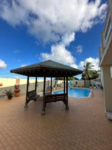 a pavilion with two benches next to a swimming pool at Apartement Anabela in Willemstad