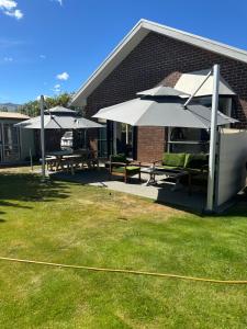 a patio with two picnic tables and umbrellas at Omara-more in Omarama