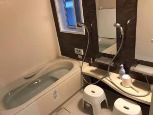 ein Badezimmer mit einer Badewanne, einem WC und einem Spiegel in der Unterkunft VILLA TAKAYAMA in Takayama