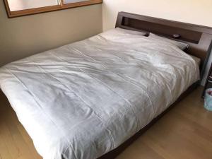 Bett mit weißer Bettwäsche und einem Kopfteil aus Holz in der Unterkunft VILLA TAKAYAMA in Takayama