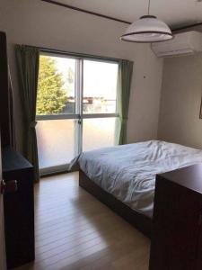 ein Schlafzimmer mit einem Bett und einem großen Fenster in der Unterkunft VILLA TAKAYAMA in Takayama