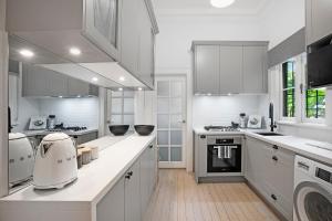 a kitchen with white cabinets and a white appliance at Beautiful victorian garden apartment, with pool. in Sydney