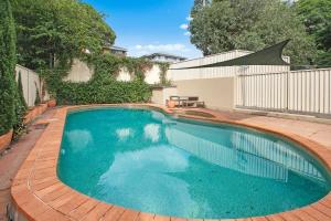a swimming pool in a yard with a fence at Beautiful victorian garden apartment, with pool. in Sydney