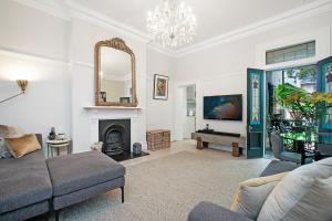 a living room with a couch and a fireplace at Beautiful victorian garden apartment, with pool. in Sydney