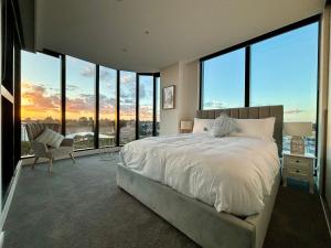 1 dormitorio con 1 cama grande y ventanas grandes en Skygarden Luxury Condo, en Glen Waverley