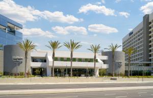 un edificio con palmeras frente a una calle en Hilton Los Angeles-Culver City, CA, en Los Ángeles