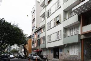 een hoog wit gebouw in een stadsstraat met auto's bij Loft Master Coração Centro Histórico livre de enchentes in Porto Alegre
