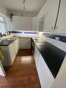 a kitchen with white cabinets and a black counter top at Spacious three bedroom property in Penrhyn bay - sleeps 6 in Penrhyn Bay