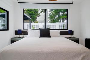 um quarto com uma grande cama branca e 2 janelas em Villa Azure Ocean Park's Seaside Luxe Retreat em San Juan