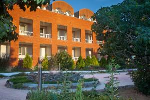 a red brick building with a garden in front of it at Rahat Hotel in Aktau