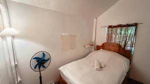 a small bedroom with a bed with a fan at Islo Hut Kaliwa in General Luna