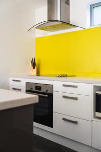 cocina con pared amarilla y fogones en Urban Sanctuary on Union en Dunedin