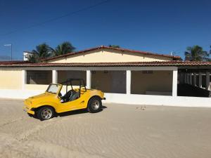 un pequeño coche amarillo estacionado frente a una casa en Oasis De Areia Casa a Beira Mar na Praia de Zumb, en Rio do Fogo