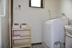 małą łazienkę z białą lodówką i umywalką w obiekcie Peace & Harmony w mieście Nagoja