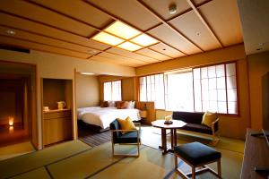 Hida Takayama Onsen Hida Hotel Plaza في تاكاياما: غرفة فندقية بسرير وطاولة وكراسي