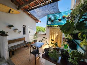 uma varanda com plantas e uma mesa e um banco em CaliForte House em Cabo Frio