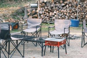 一軒家貸切 ARUYOguesthouse BBQと焚き火ができる宿 : مجموعة من الكراسي وطاولة أمام كومة من الخشب