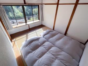 Cama pequeña en habitación con ventana en 一軒家貸切 ARUYOguesthouse BBQと焚き火ができる宿 