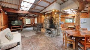 a living room with a table and a stone fireplace at Crayfish Creek Van & Cabin Park in Crayfish Creek