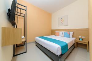 a bedroom with a bed and a flat screen tv at Sans Hotel Cibanteng Dramaga Bogor in Bogor