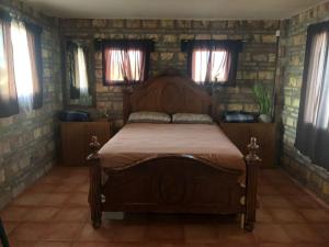 a bedroom with a wooden bed in a stone wall at Apartamento Tony Chumpos Superior in San Felipe