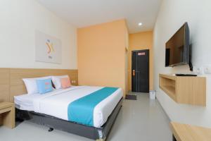 1 dormitorio con 1 cama y TV de pantalla plana en Sans Hotel Cibanteng Dramaga Bogor en Bogor