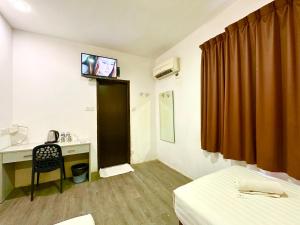 Habitación con cama, escritorio y TV. en Park Hotel, en Kota Kinabalu