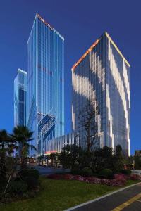 two tall glass buildings in a city with a park at Wanda Realm Jiangmen in Jiangmen