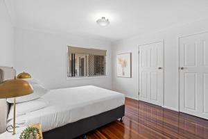 Windsor Cosy 2-Bedroom Unit in Quiet Neighborhood في بريزبين: غرفة نوم بيضاء مع سرير ومرآة