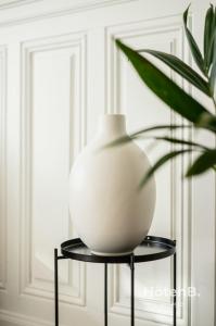 a white vase on a black stand next to a plant at The "Heritage" Heart of Limoges Parking AC and Private Terrace in Limoges