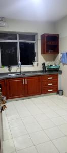 - une cuisine avec des placards en bois, un évier et 2 fenêtres dans l'établissement Luzira port bell lake side apartment, à Kampala