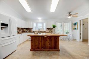 a kitchen with white appliances and a wooden island at Sovereign Cottage - Farm Land/Hot Tub/Outdoor Area in Fuquay-Varina