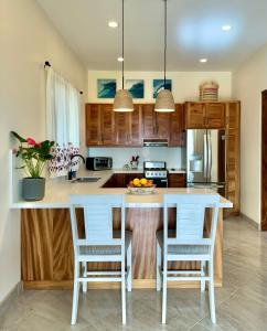 een keuken met houten kasten en een wit kookeiland met stoelen bij Brand NEW Casita Clásica in El Pescadero