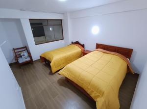 1 Schlafzimmer mit 2 Betten mit gelber Bettwäsche und einem Fenster in der Unterkunft LOS NEVADOS II in Huaraz