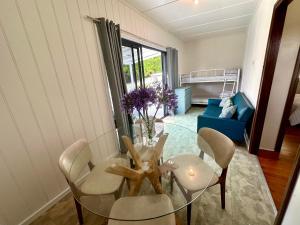 a dining room with a glass table and chairs at Kioloa Beach Cabins in Kioloa