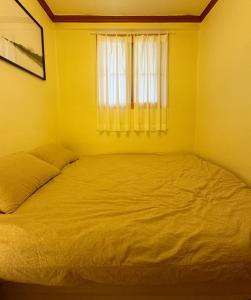 Cama en habitación amarilla con ventana en La Tulipe, en Seúl