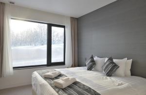 a bedroom with a large white bed with a window at ZEN - Vacation STAY 74302v in Niseko