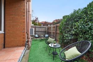 eine Terrasse mit Stühlen, Tischen und einem Zaun in der Unterkunft Urban Retro - Experience Vibrant Courtyard Charm in Melbourne