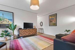 ein Wohnzimmer mit einem Sofa und einem Flachbild-TV in der Unterkunft Urban Retro - Experience Vibrant Courtyard Charm in Melbourne