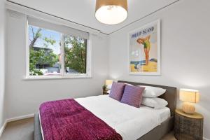 ein Schlafzimmer mit einem Bett mit einer lila Decke in der Unterkunft Urban Retro - Experience Vibrant Courtyard Charm in Melbourne