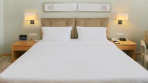 Holiday Inn Beijing Deshengmen, an IHG Hotel في بكين: غرفة نوم بسرير كبير مع وسادتين بيضاء